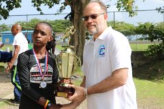 CARICOM Secretary-General Ambassador Irwin LaRocque presents the 1st Place Trophy to repeat winner Linda McDowald of Saint Vincent and the Grenadines
