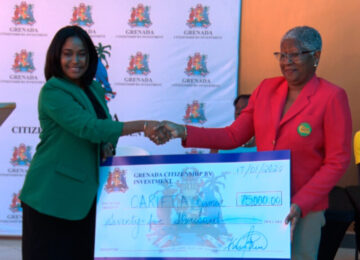 Image of a woman shaking hands and handing over check to another woman.