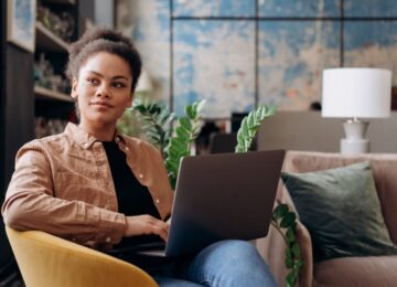 Image of woman sitting on chair with a laptop on her lap.